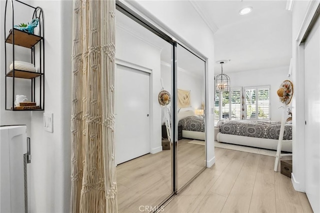 bedroom featuring crown molding, recessed lighting, a closet, light wood-style flooring, and an inviting chandelier