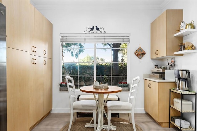 dining area featuring ornamental molding, light wood-type flooring, and baseboards