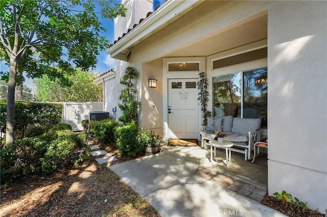 view of exterior entry featuring a patio area, fence, and stucco siding