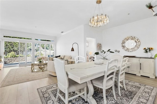 dining space with light wood-style floors, crown molding, and an inviting chandelier