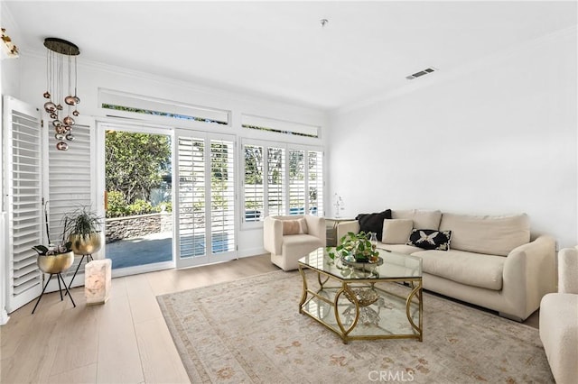 living area featuring visible vents, wood finished floors, and ornamental molding