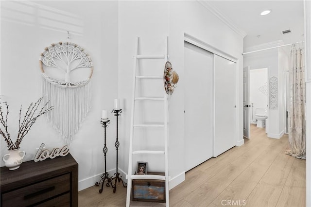 corridor with light wood finished floors, baseboards, and ornamental molding