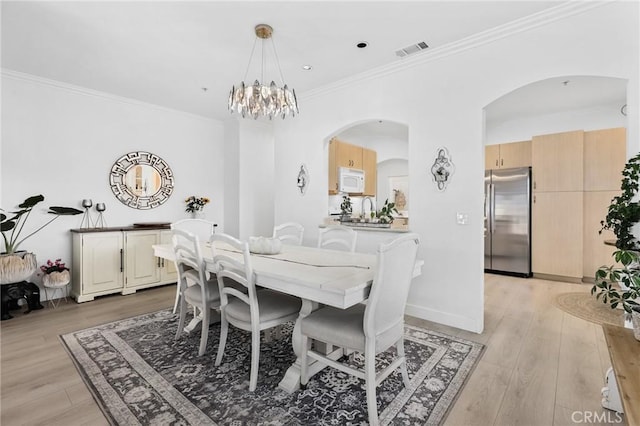 dining room with light wood-style floors, visible vents, crown molding, and a notable chandelier