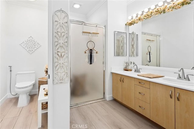 bathroom with ornamental molding, a stall shower, a sink, and wood finished floors