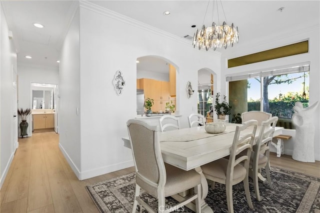 dining room featuring arched walkways, visible vents, ornamental molding, light wood-type flooring, and baseboards