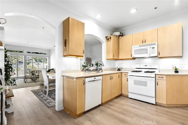 kitchen featuring white appliances, light countertops, a sink, and light brown cabinetry