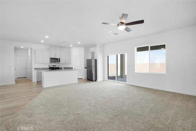 unfurnished living room featuring recessed lighting, visible vents, a ceiling fan, light carpet, and baseboards