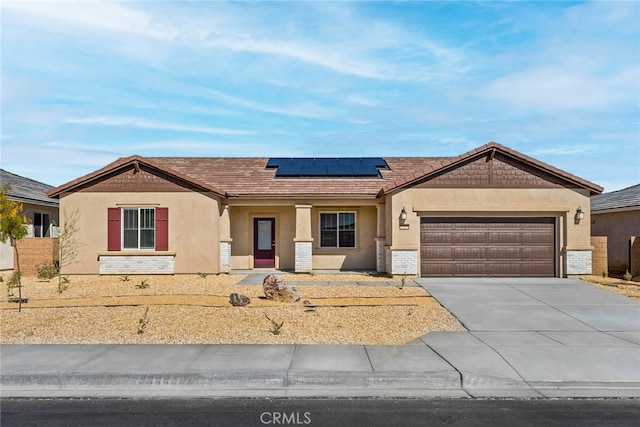 single story home featuring a garage, concrete driveway, roof mounted solar panels, and stucco siding