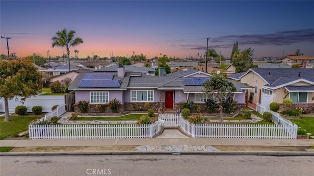 view of front of home featuring a fenced front yard, a residential view, and solar panels