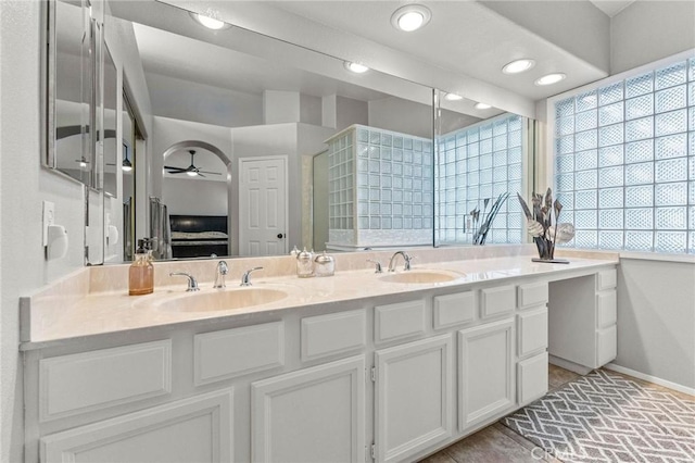 full bathroom featuring a sink, baseboards, ensuite bath, and double vanity