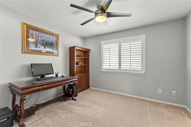 carpeted office with a ceiling fan and baseboards