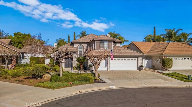 mediterranean / spanish home featuring concrete driveway, a tiled roof, an attached garage, and stucco siding