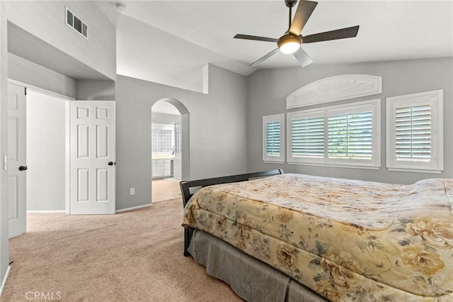 carpeted bedroom featuring visible vents, ensuite bathroom, arched walkways, baseboards, and ceiling fan