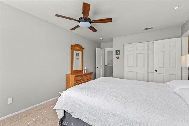 carpeted bedroom with visible vents, baseboards, a closet, and a ceiling fan