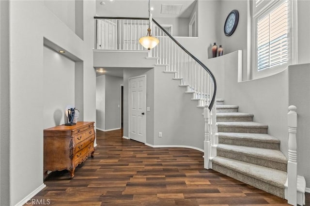 interior space with stairs, wood finished floors, baseboards, and a towering ceiling