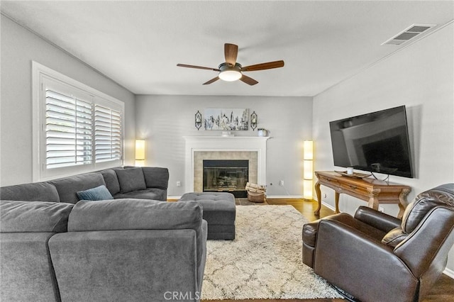 living room with visible vents, wood finished floors, a fireplace, baseboards, and ceiling fan