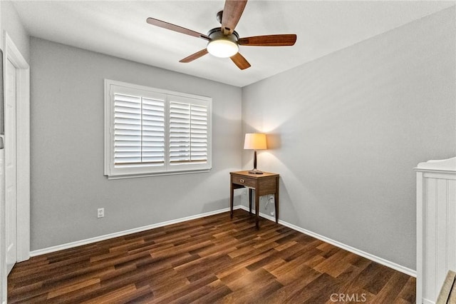 empty room featuring dark wood-style floors, baseboards, and ceiling fan