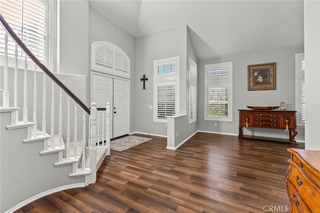 foyer entrance featuring stairway, high vaulted ceiling, baseboards, and wood finished floors