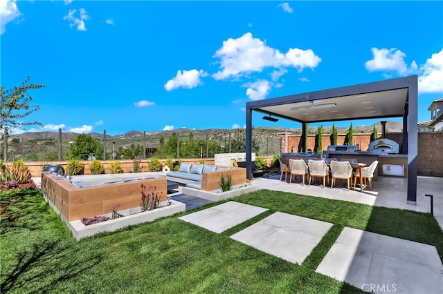 view of yard featuring a patio, outdoor lounge area, an outdoor kitchen, a mountain view, and fence