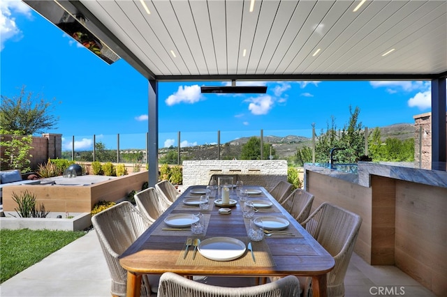 view of patio / terrace featuring outdoor dining area, fence, and a mountain view