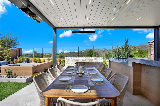 view of patio / terrace with outdoor dining area, fence, and a mountain view