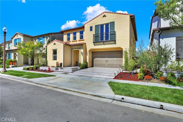 mediterranean / spanish-style home with driveway, a balcony, a tiled roof, an attached garage, and stucco siding