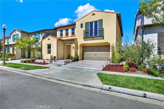 mediterranean / spanish-style home featuring stucco siding, concrete driveway, a garage, a balcony, and a tiled roof