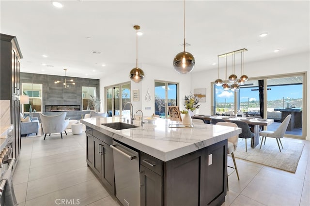 kitchen featuring recessed lighting, stainless steel dishwasher, a sink, a tile fireplace, and a kitchen breakfast bar