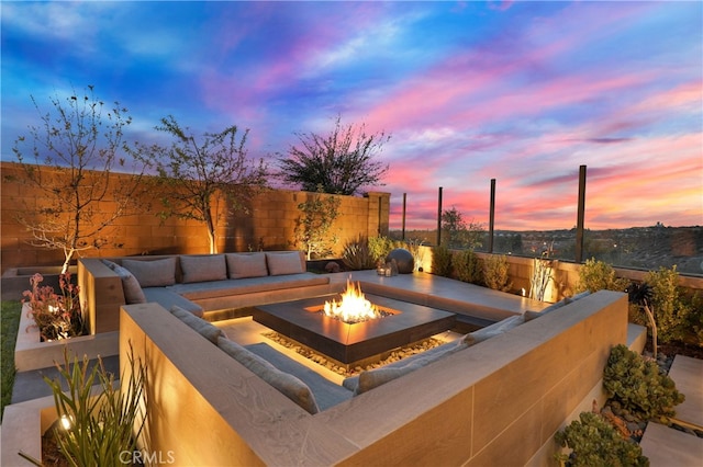 patio terrace at dusk featuring an outdoor fire pit and a fenced backyard