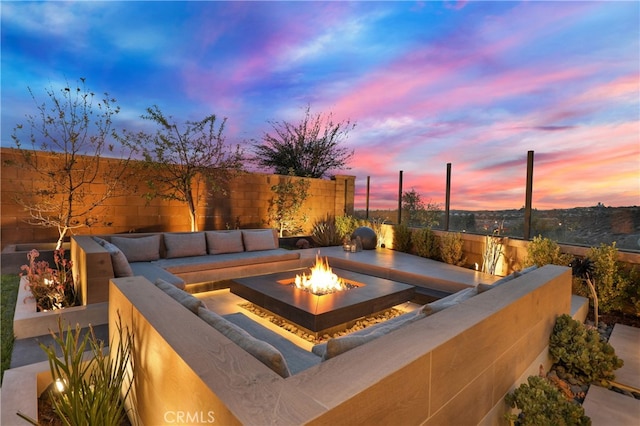patio terrace at dusk with an outdoor fire pit and a fenced backyard