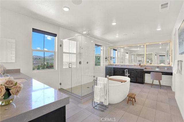 full bathroom featuring a sink, two vanities, visible vents, a soaking tub, and a shower stall