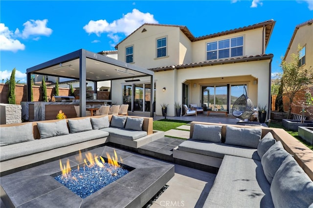 back of house with a tile roof, a patio area, an outdoor living space with a fire pit, and stucco siding