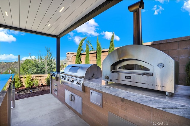 view of patio with fence, grilling area, and an outdoor kitchen