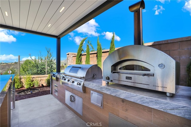 view of patio featuring area for grilling, fence private yard, and an outdoor kitchen