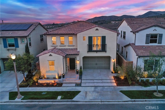 mediterranean / spanish-style house featuring stucco siding, a mountain view, a balcony, driveway, and a tiled roof