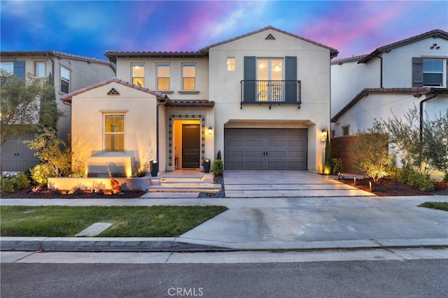 mediterranean / spanish-style home featuring a balcony, a garage, driveway, a tiled roof, and stucco siding