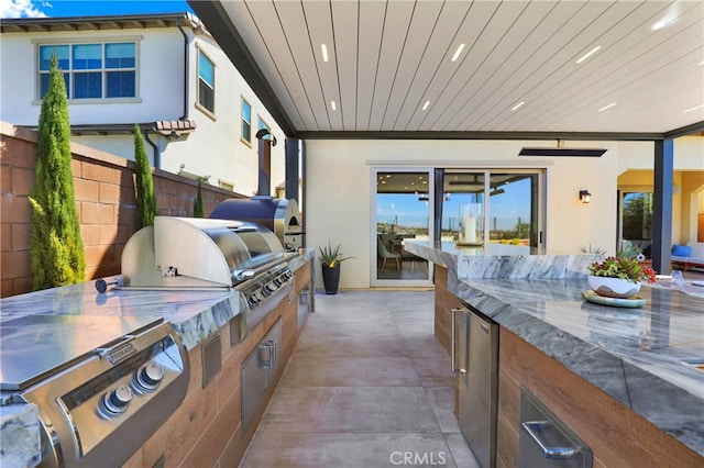 view of patio with area for grilling, an outdoor kitchen, and fence