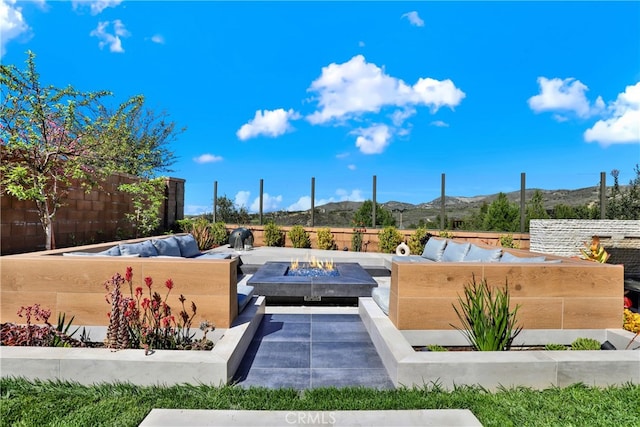 view of pool with an outdoor living space with a fire pit, fence, and a mountain view