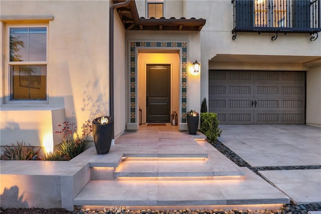 doorway to property with stucco siding, driveway, and a garage