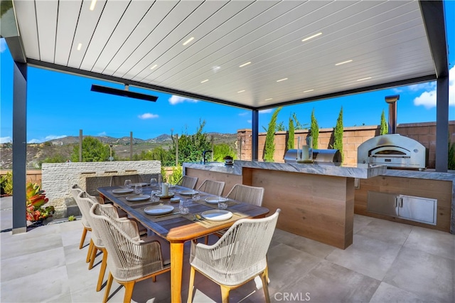 view of patio featuring a grill, fence, a mountain view, and an outdoor kitchen