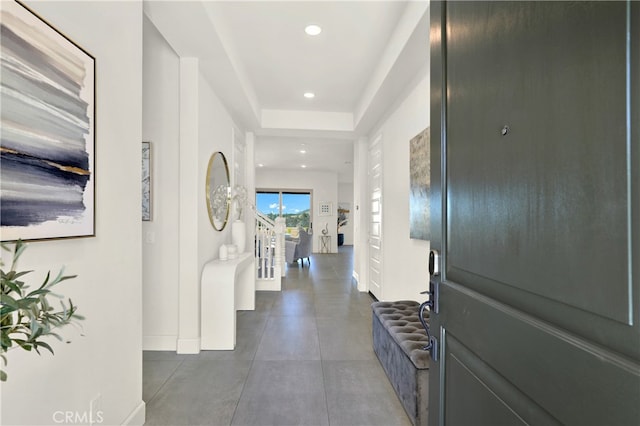 hall featuring stairs, baseboards, a tray ceiling, and recessed lighting