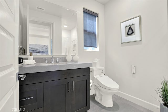 bathroom featuring toilet, vanity, visible vents, baseboards, and walk in shower