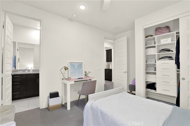 bedroom with light carpet, baseboards, ensuite bathroom, a sink, and a closet