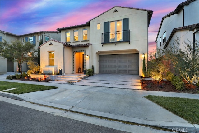 mediterranean / spanish-style home featuring concrete driveway, an attached garage, and stucco siding