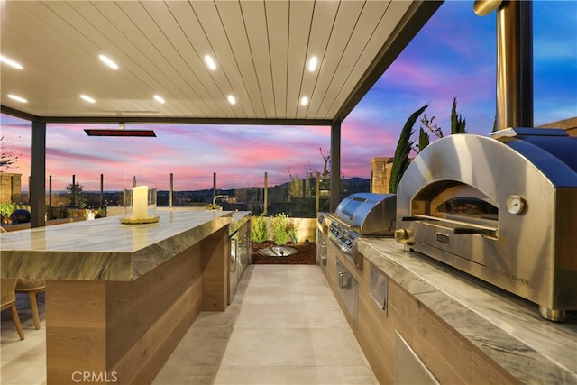 patio terrace at dusk with area for grilling and exterior kitchen