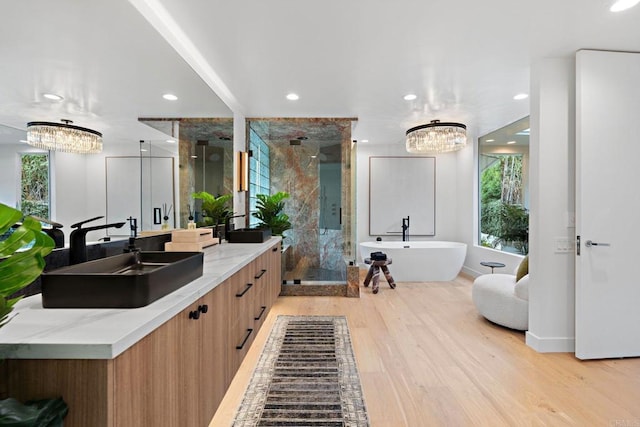 full bathroom with wood finished floors, a freestanding bath, a shower stall, a sink, and recessed lighting