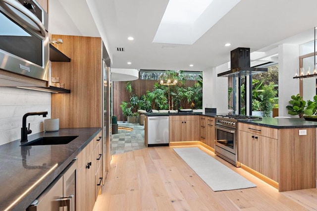 kitchen with a sink, light wood-type flooring, stainless steel range, modern cabinets, and island exhaust hood