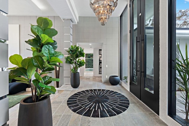 foyer with a chandelier, french doors, beamed ceiling, and tile walls