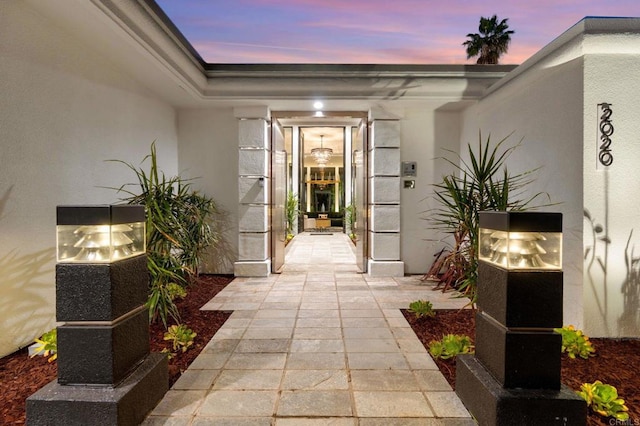 exterior entry at dusk featuring stucco siding