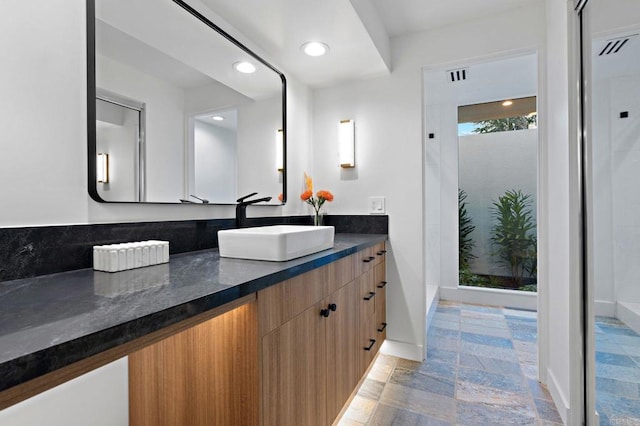 full bath featuring stone finish flooring, recessed lighting, vanity, and baseboards